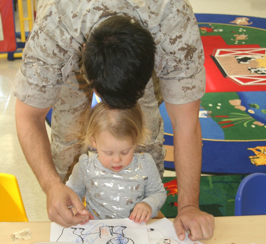 Abigail, 3, colors a picture with the help of her dad, Chaplain Loren Crone, at the Teddy Bear Clinic Apr. 8.