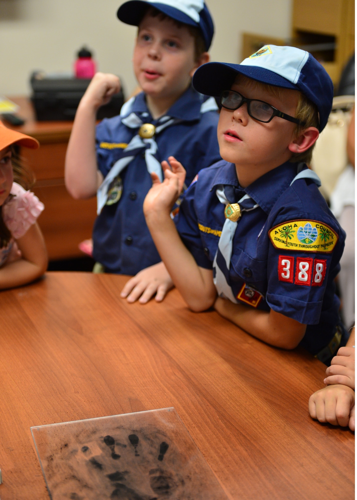 Cub Scouts from Pack 388 watch as members of the 647th Security Forces Squadron demonstrate  different methods used to lift finger prints during a tour of the 647th SFS on Joint Base Pearl Harbor-Hickam, April 5, 2016. During the tour, members of the 647th SFS provided weapon, fingerprint and vehicle demonstration to the Cub Scouts in Den Five of Pack 388. (U.S. Air Force photo by Tech. Sgt. Aaron Oelrich/Released)