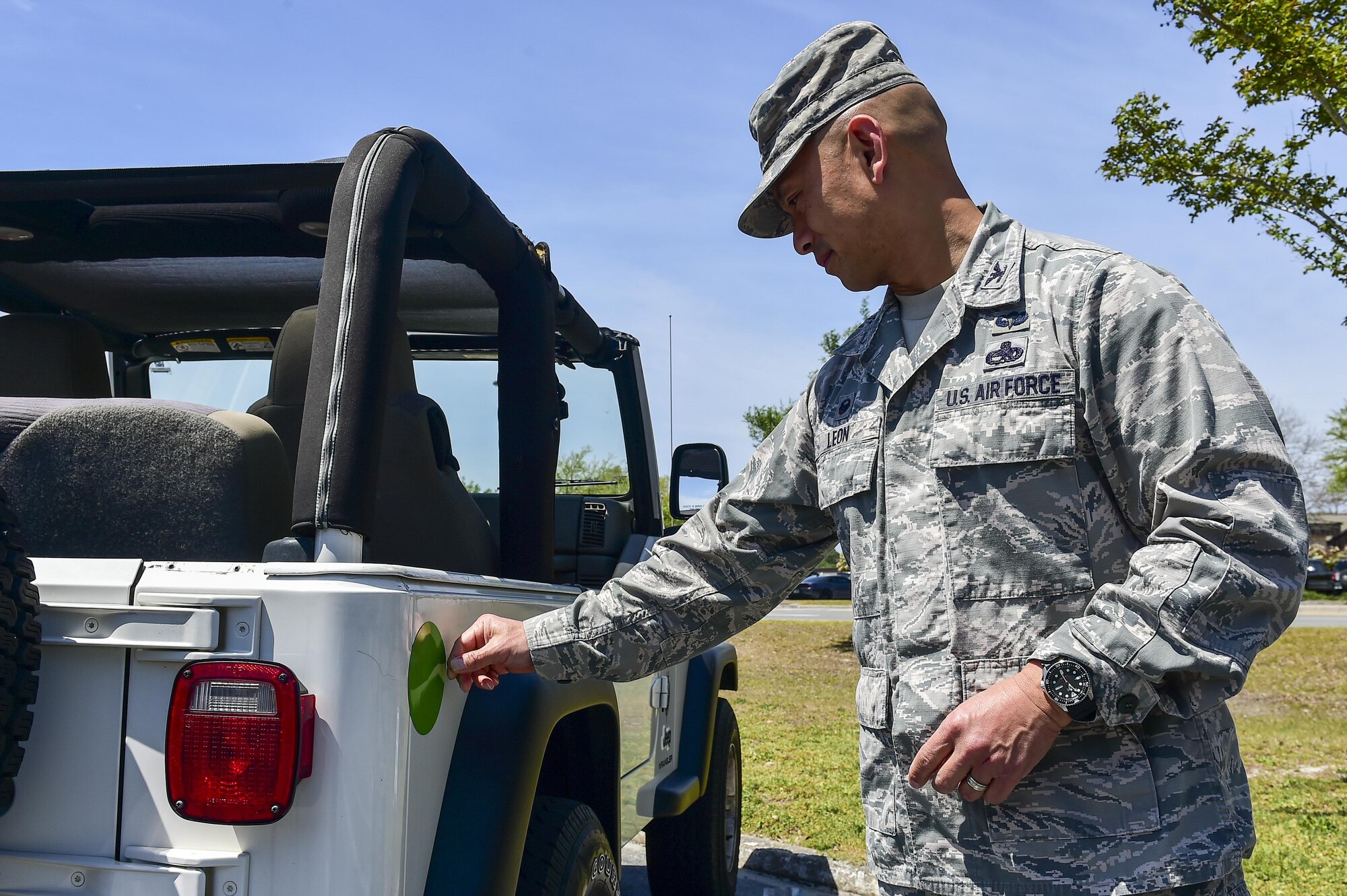 Col. Rene Leon, the commander of the 1st Special Operations Group, places a green dot magnet on his car at Hurlburt Field, Fla., April 6, 2016. Green Dot prepares organizations to implement a strategy of violence prevention that reduces power-based interpersonal violence, including sexual violence, domestic violence, dating violence, stalking, child abuse, elder abuse and bullying. (U.S. Air Force photo by Senior Airman Jeff Parkinson)