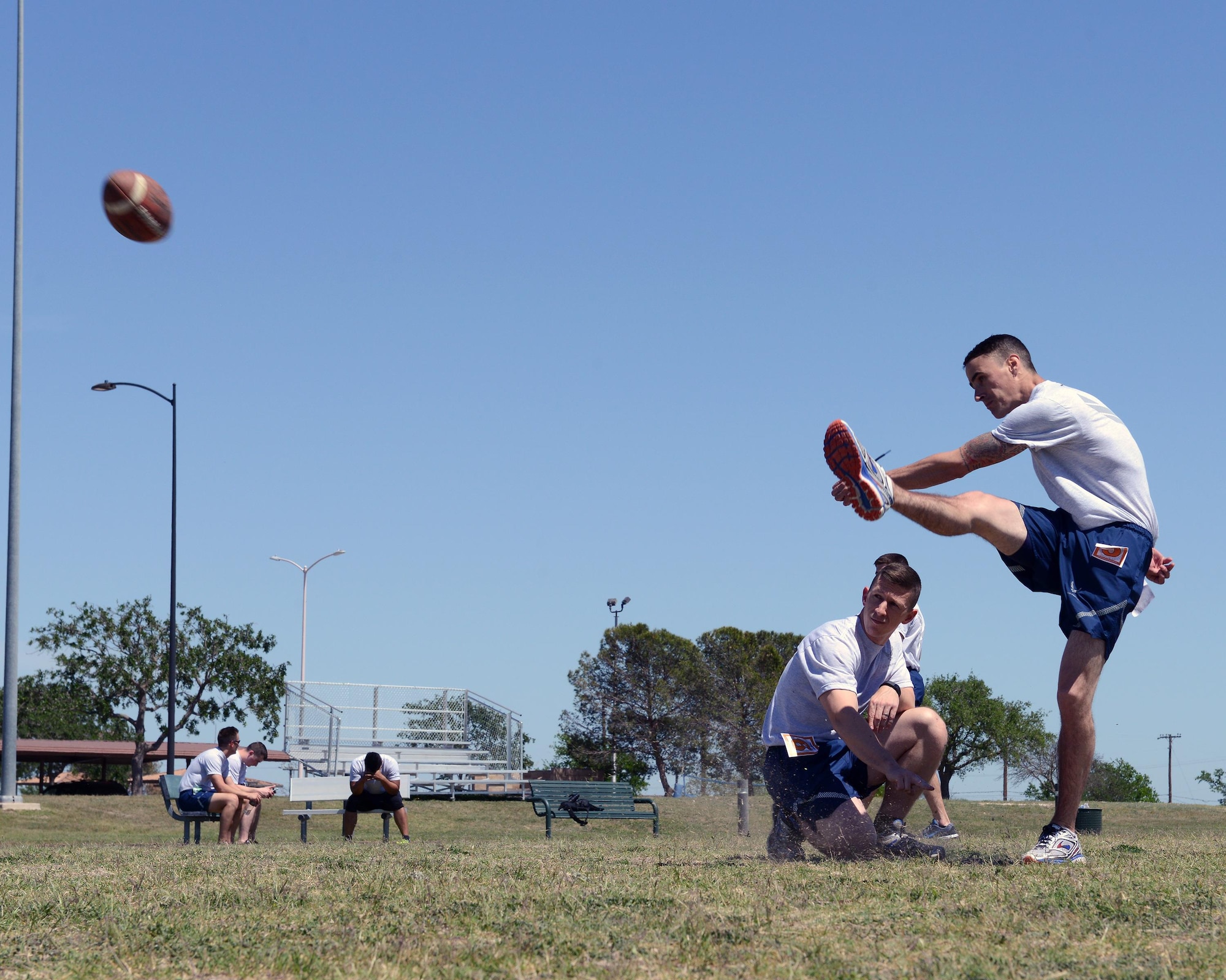 2nd Lt. John Silvi, 47th Student Squadron awaiting pilot training, right, kicks a football on the field at Laughlin Air Force Base, Texas, April 5, 2016. The Warrior Games was an opportunity to change up physical training by challenging students through competitive events. (U.S. Air Force photo by Senior Airman Jimmie D. Pike)