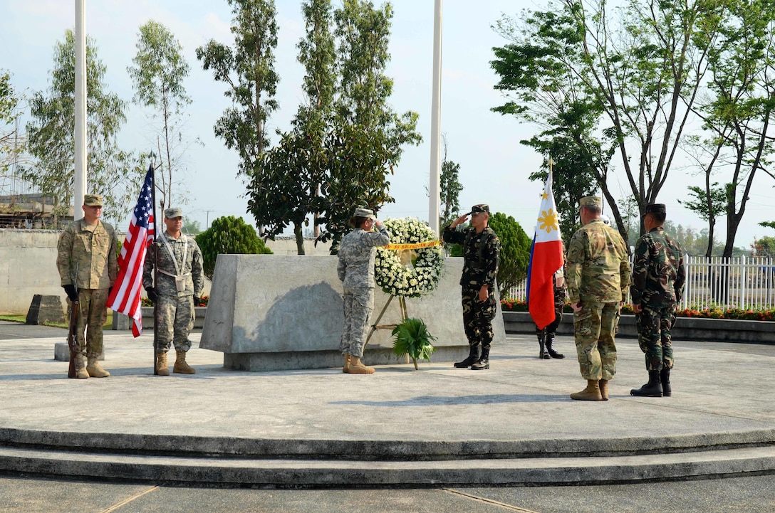 Soldiers from the 445th Civil Affairs Battalion, 324th PSYOP Company, and 7th Infantry Division, Armed Forces of the Philippines salute as they lay a wreath at the Cabanatuan POW Memorial, April 11, 2016.