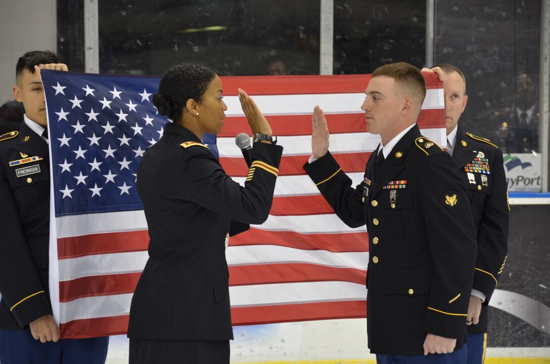 U.S. Army Maj. Corinne Bell, commander of the 689th Rapid Port Opening Element, reenlists Spc. Timothy Scheid, 689th RPOE information technology specialist, during a Norfolk Admirals Hockey Game in Norfolk, Va., April 9, 2016. Scheid has played hockey for 11 years and has attended 15 Admiral games since moving to the area in August. (U.S. Army photo by Loran Doane)