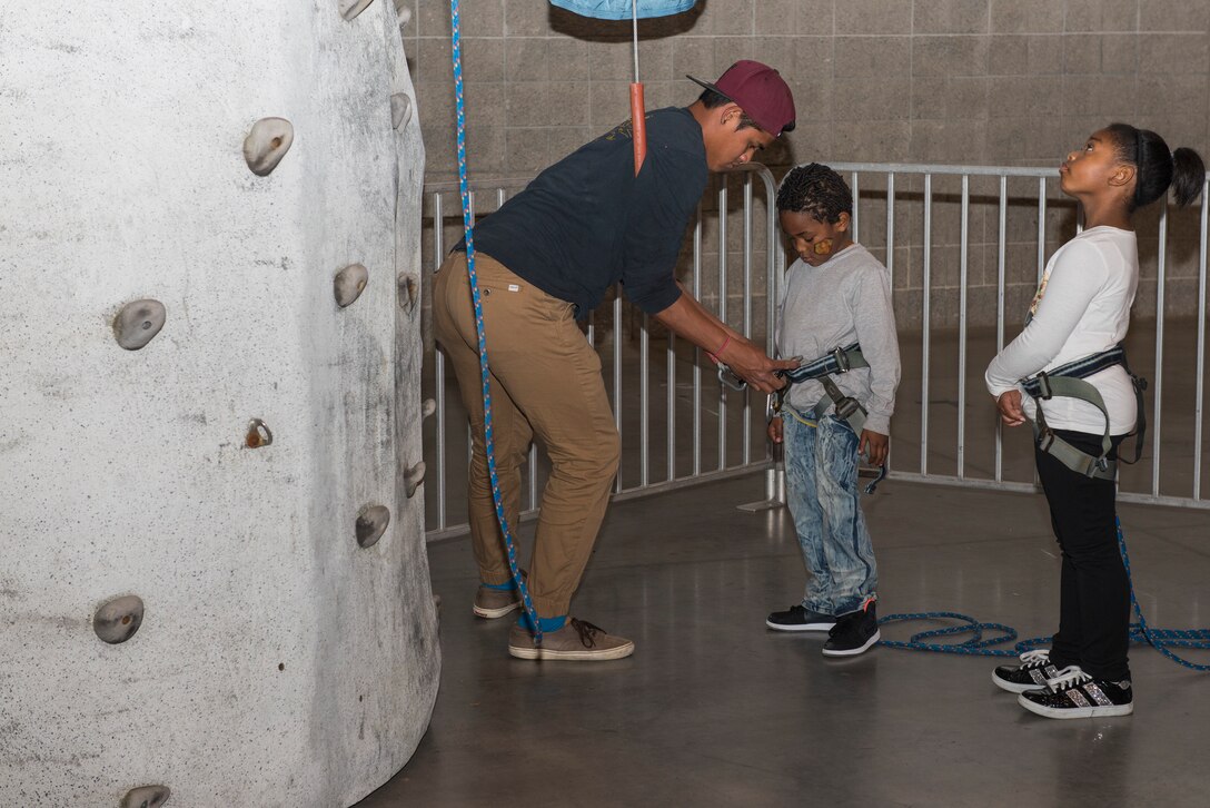 A volunteer straps a harness on a child during the “Seussabration” event in Hampton, Va., April 9, 2016. The event showed appreciation to military families and the challenges experienced by military children. (U.S. Air Force photo by Airman 1st Class Derek Seifert)