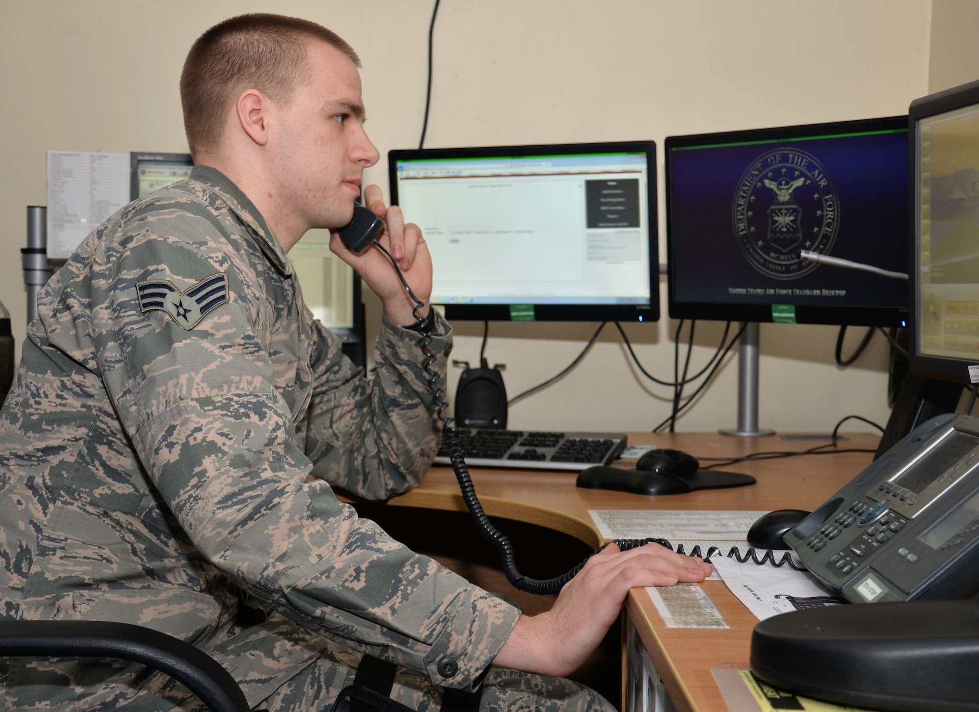 U.S. Air Force Senior Airman Niklas Mlynarski, 100th Security Forces Squadron combined controller, answers phone calls from different base agencies, March 21, 2016, on RAF Mildenhall, England. By being quick to answer the telephone, Mlynarski can quickly dispatch security forces patrols to those in need. (U.S. Air Force photo by Gina Randall/Released)