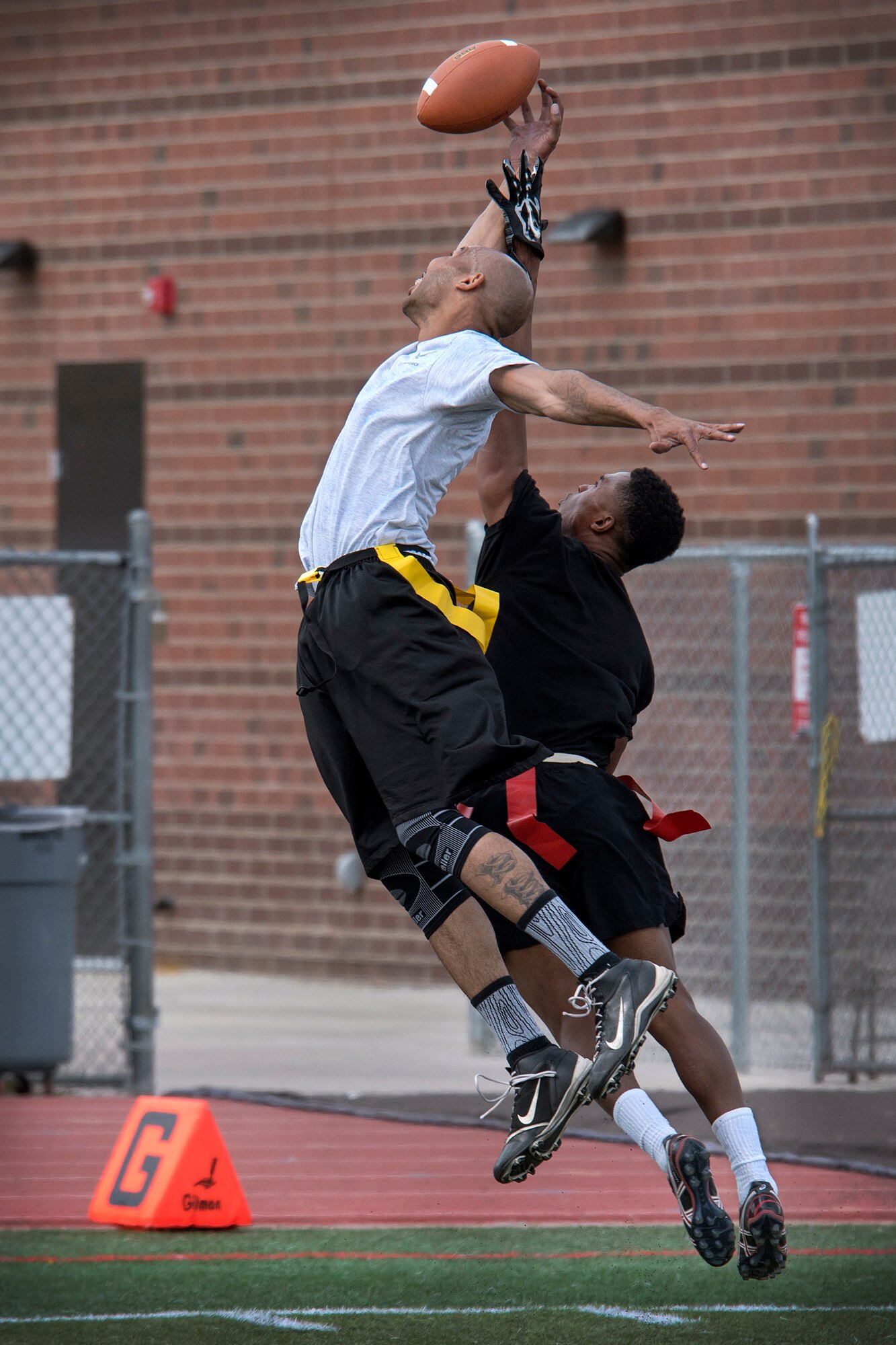 COLORADO SPRINGS, Colo. – An Air Force flag football player reaches to catch a pass while a Fort Carson player attempts to block his opponent during a spring game scrimmage on April 9, 2016 at Falcon-Fort Carson High School. Players from fort Carson and from Peterson Air Force Base/Schriever AFB participated in the flag football game. Local military leaders watched the game from the sidelines. (U.S. Air Force Photo by Craig Denton)
