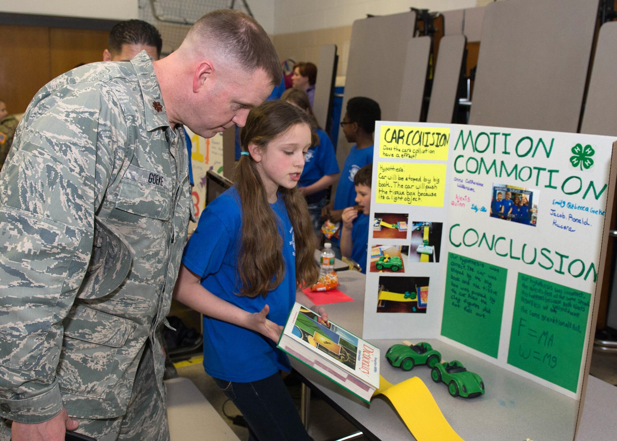Maj. Robert Goeke, C3I and Networks contracting officer, and his daughter, Emily, look over her Hanscom Science Share project at the base primary school April 12. The science share event began with welcoming remarks from installation leadership followed by an opportunity to meet with students about the projects they have worked on for more than a month. (U.S. Air Force photo by Jerry Saslav)