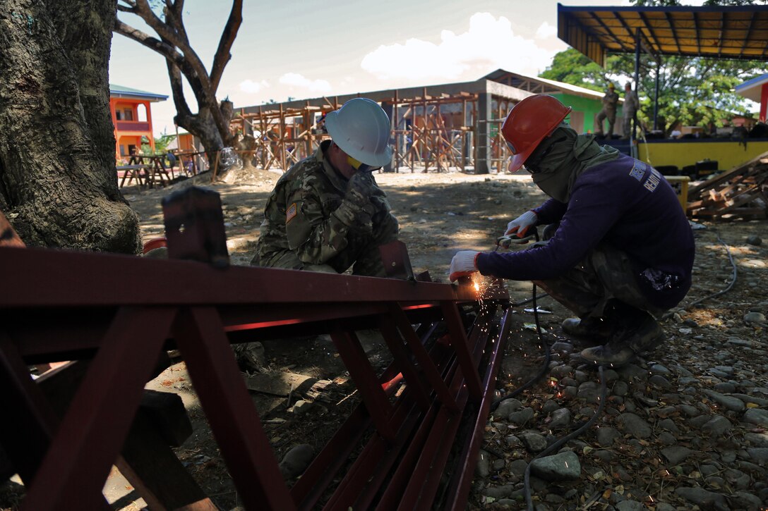 Philippine Navy 1st Class steelworker Darwin G Ballecer welds a roof trusses for a multipurpose facility with U.S. Army Spc. Trevor Bass, a carpentry masonry specialist with 130th Engineer Brigade, in Matahimik-Bucana elementary school in Puerto Princesa, Philippines during exercise Balikatan April 8, 2016.  Balikatan, which means "shoulder to shoulder" in Filipino, is an annual bilateral training exercise focused on improving the ability of Philippine and U.S. military forces to work together during planning, contingency and humanitarian assistance and disaster relief operations.