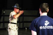 A poolee with Marine Corps Recruiting Station Twin Cities stands at attention as one of the three drill instructors in attendance educate the future Marines on customs and courtesies at the RS Twin Cities Family Night, April 9. During the family night, drill instructors, RS staff and guest speakers informed families on what to expect at recruit training. 