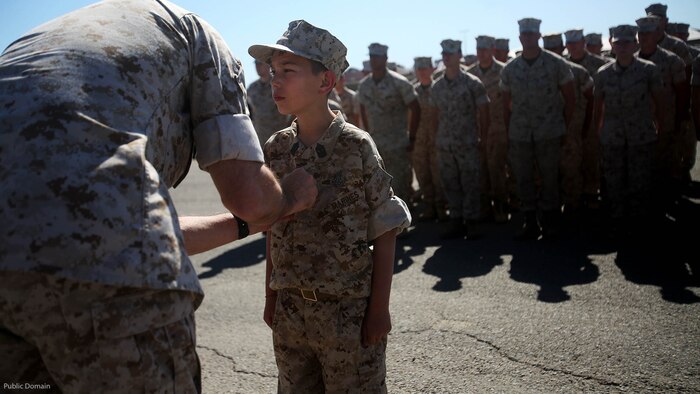 Nathan Aldaco, a 12 year-old boy with hypoplastic left heart syndrome, stands at attention as Col. Jaime O. Collazo pins on the Master EOD badge during a Make-A-Wish event supported by 7th Engineer Support Battalion, 1st Marine Logistics Group, at Marine Corps Base Camp Pendleton, California, March 24, 2016. Collazo is the 1st MLG chief of staff. Marines with 7th ESB and Explosive Ordnance Disposal helped to make Nathan’s wish of training with Marines come true by demonstrating the capabilities of their EOD robots and detonating TNT, C4, dynamite and blasting caps, while the heavy equipment operators gave him the opportunity to ride the D7 dozer and the excavator, in which he dug a pit, built a berm, and broke several large tree trunks. 