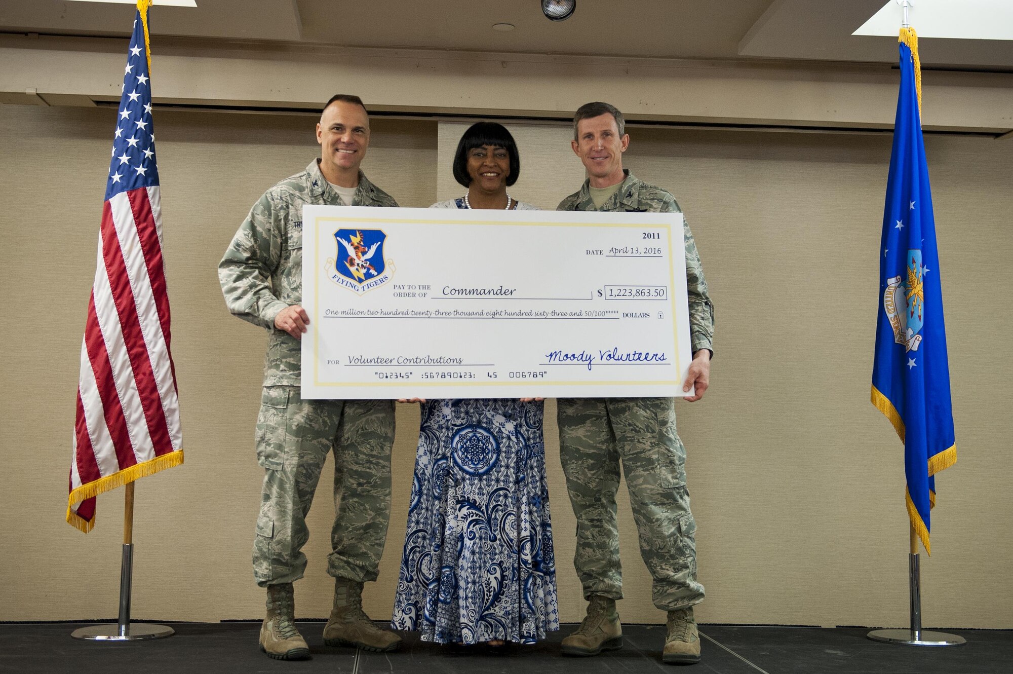 Gail Brown, 23d Force Support Squadron community readiness specialist, presents U.S. Air Force Col. Thomas Kunkel, 23d Wing commander, with a symbolic check during a volunteer recognition ceremony, April 13, 2016, at Moody Air Force Base, Ga. The check symbolized the money value of the volunteer hours that Team Moody contributed during 2015, an amount totaling $1,223,863.50. (U.S. Air Force photo by Airman 1st Class Lauren M. Hunter/Released) 