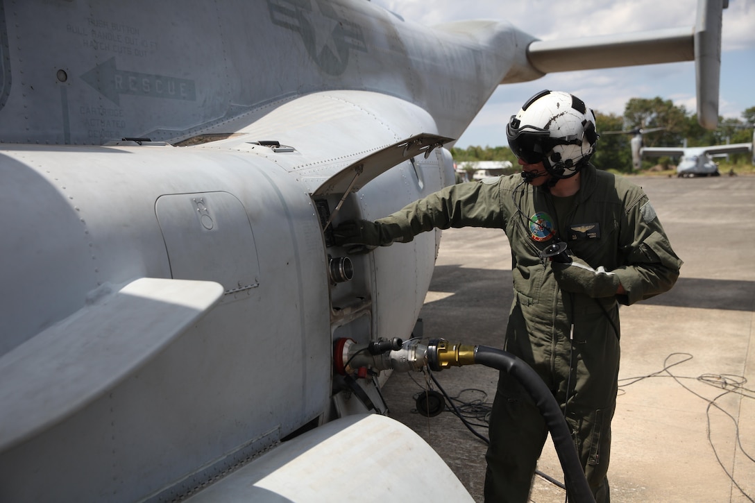 U.S. Marine Sgt. Anthony Dicola makes adjustments to an MV-22B Osprey while it pumps fuel at an aerial delivery ground refueling station to refuel a U.S. Army UH-60 Black Hawk during Balikatan 16, in San Fernando, Philippines, April 12, 2016. Dicola is from Omaha Nebraska and a MV-22 crew chief for Marine Medium Tilt-rotor Squadron 262, Marine Aircraft Group 36, 1st Marine Aircraft Wing, III Marine Expeditionary Force. After establishing the ADGR, the Marines of VMM-262 refueled multiple U.S. Army aircrafts from Bravo 3-25, Aviation Regiment via the MV-22B Osprey.