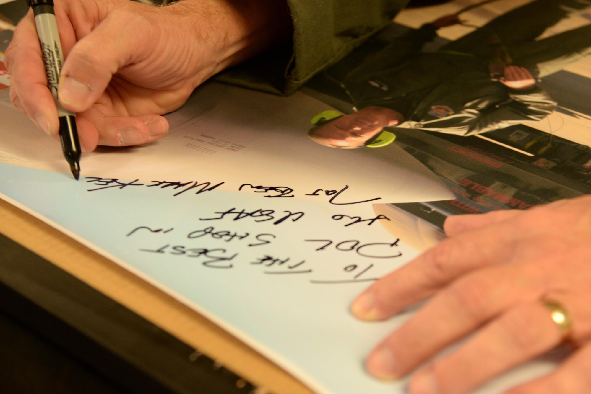 Maj. Gen. Mark Kelly, 9th Air Force commander, signs a picture of himself following a visit with 4th Logistics Readiness Squadron Airmen April 8, 2016, at Seymour Johnson Air Force Base, North Carolina. Kelly, a former 4th Fighter Wing commander, took the photograph after fueling an F-15E Strike Eagle aircraft during his tenure as commander here. (U.S. Air Force photo/Staff Sgt. Chuck Broadway)