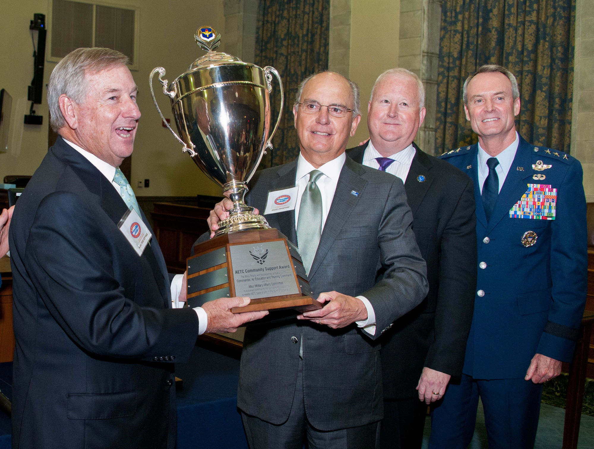 (From left) Montgomery Mayor Todd Strange and Bruce Crawford, chairman of the board of directors for the Montgomery Area Chamber of Commerce, accept the 2015 Altus Trophy on behalf of the city of Montgomery during a ceremony at the U.S. Federal Courthouse April 11, 2016, from Dr. Joe Leverett, chairman of the Altus Trophy selection committee, and Lt. Gen. Darryl Roberson, commander of Air Education and Training Command. (U.S. Air Force photo by Donna Burnett)