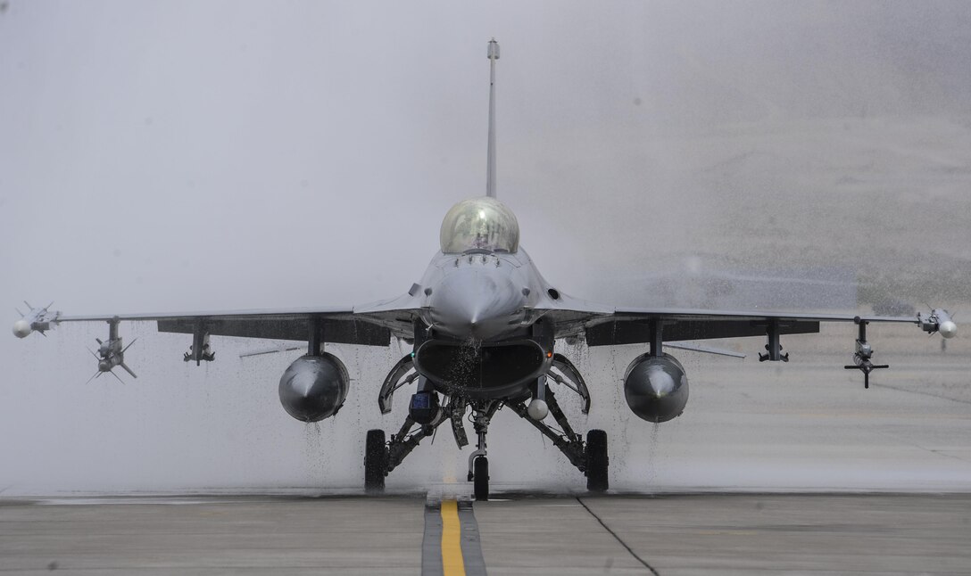 Col. Aaron Steffens, 57th Wing vice commander, taxis down the runway in an F-16 Fighting Falcon after being sprayed by firetrucks during his fini flight at Nellis Air Force Base, Nev., April 8, 2016. As a pilot retires or leaves a squadron, the last flight in an aircraft is known as a fini flight. (U.S. Air Force photo by Airman 1st Class Kevin Tanenbaum)