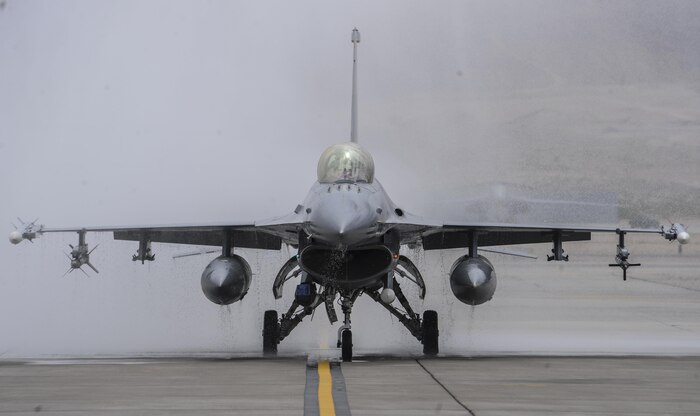 Col. Aaron Steffens, 57th Wing vice commander, taxis down the runway in an F-16 Fighting Falcon after being sprayed by firetrucks during his fini flight at Nellis Air Force Base, Nev., April 8, 2016. As a pilot retires or leaves a squadron, the last flight in an aircraft is known as a fini flight. (U.S. Air Force photo by Airman 1st Class Kevin Tanenbaum)