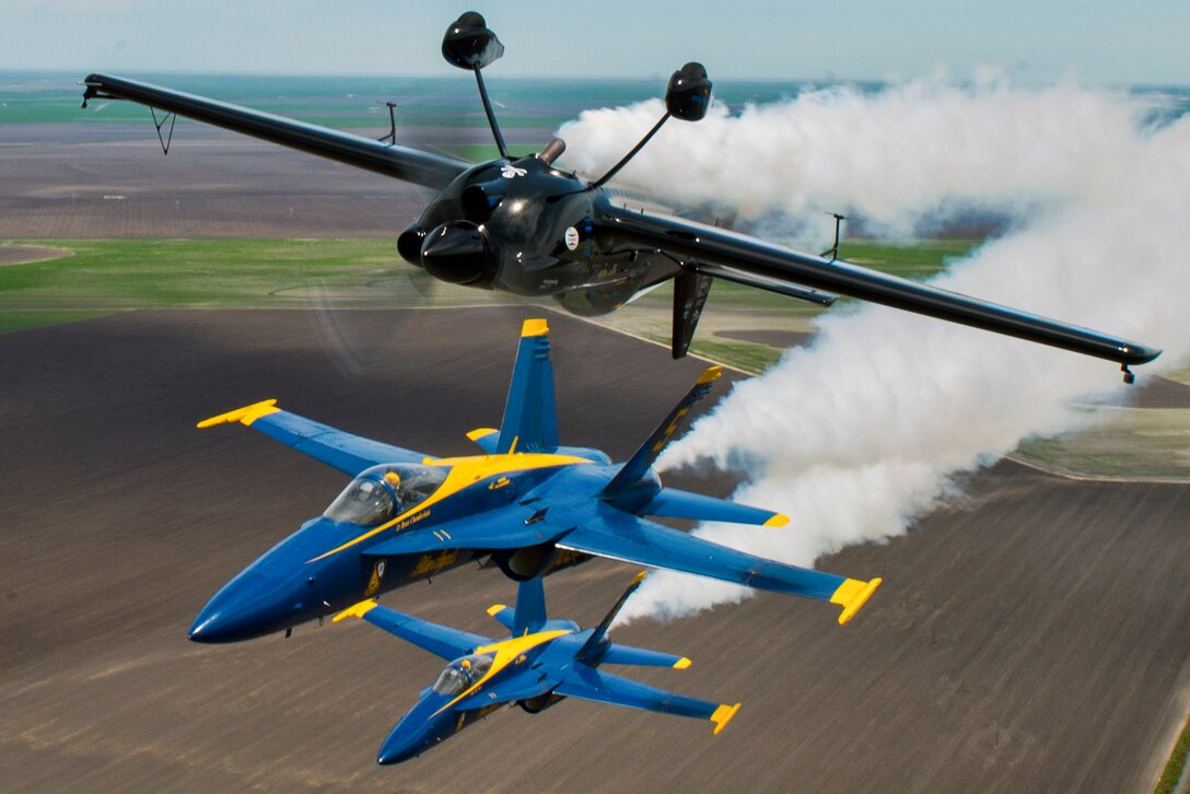 The Blue Angels lead solo, Navy Lt. Ryan Chamberlain, and opposing solo, Capt. Jeff Kuss, get into position below performer Rob Holland for a photo opportunity during Wings Over South Texas 2016 at Naval Air Station Kingsville, Texas, April 7, 2016. Navy photo by Petty Officer 2nd Class Ian Cotter