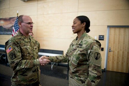 Brig. Gen. Jeffrey Doll, commander of the Army Reserve Sustainment Command, presents Capt. Arlinda Adderley, a contracting specialist with the 915th Contingency Contracting Battalion headquartered in Baltimore, Maryland, with a coin. Adderley was identified by her battalion commander as demonstrating excellent knowledge of applicable contracting policies and regulations to greatly enhance her team’s ability to successfully execute over 45 contracting actions during the six-day training event. 
