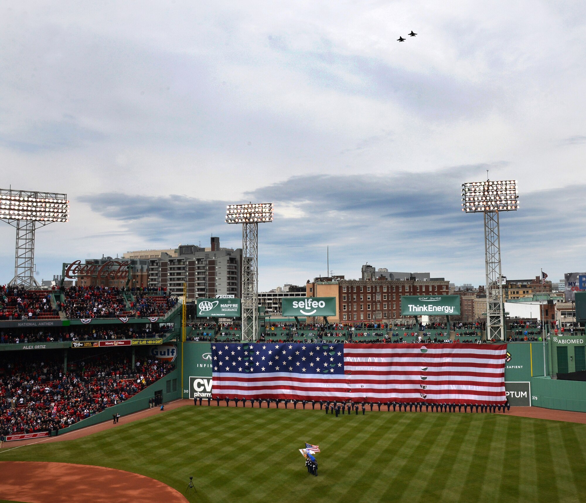 BOSTON -- Airmen from Hanscom Air Force Base, Mass., salute during the playing of the national anthem at Fenway Park for the Boston Red Sox opening day festivities April 11, while F-16s from the 158th Fighter Wing in Vermont perform a fly over and members of the Patriot Honor Guard team present the colors. Hanscom AFB has a long-standing community partnership with the Red Sox organization. (U.S. Air Force photo by Mark Herlihy)