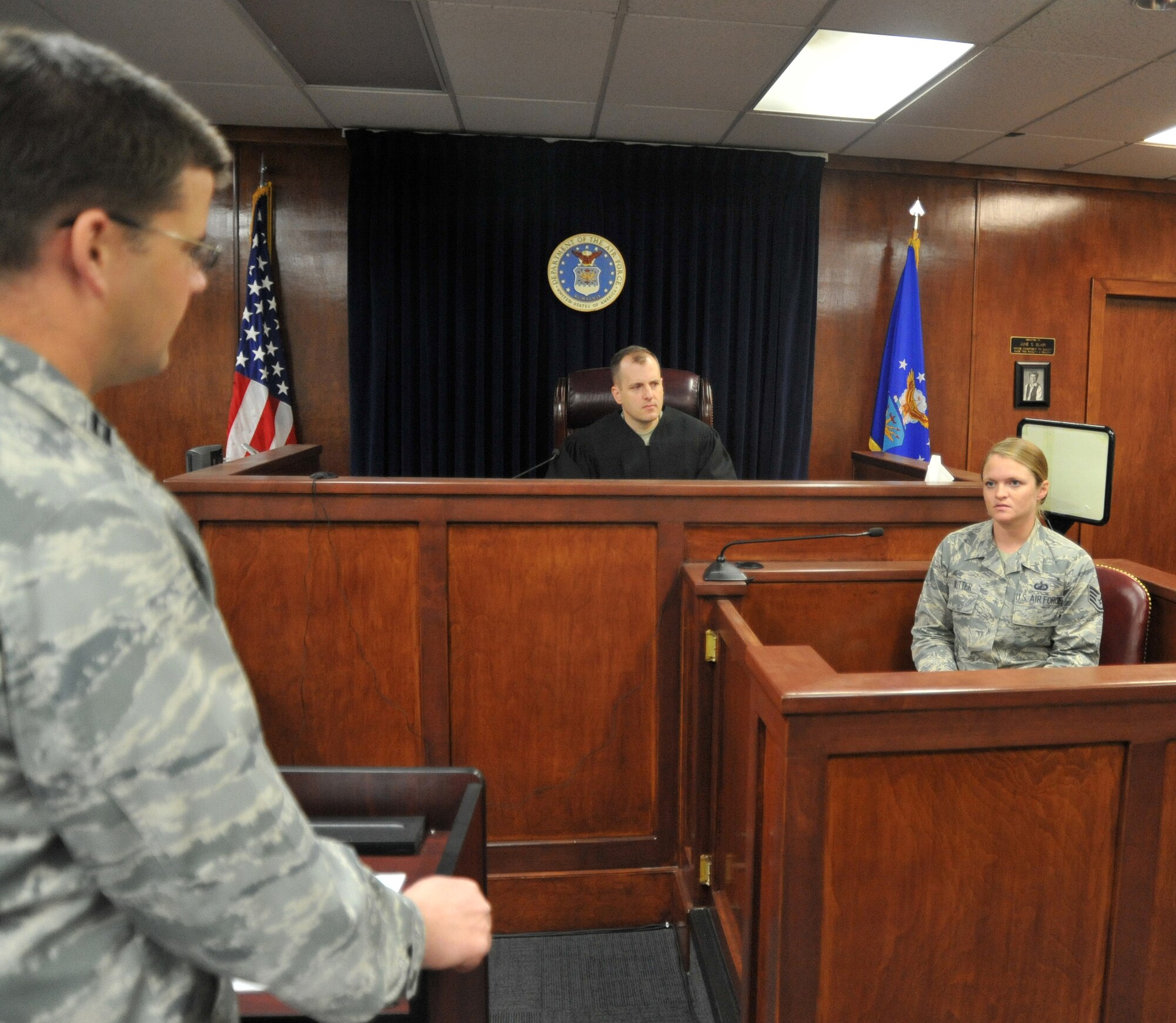 Capt. Paul Clawson (playing the defense council) grills Staff Sgt. Cassandra Nutter (playing the victim), during a rehearsal today at the Kirtland Legal Office courtroom as Maj. Dan Tull (playing the military judge) looks on. The actors engage in an intense dialogue during the production, which takes place April 15 at 1 p.m. at the Phillips Conference Center (Bldg. 201). (Air Force photo by Jim Fisher) 
