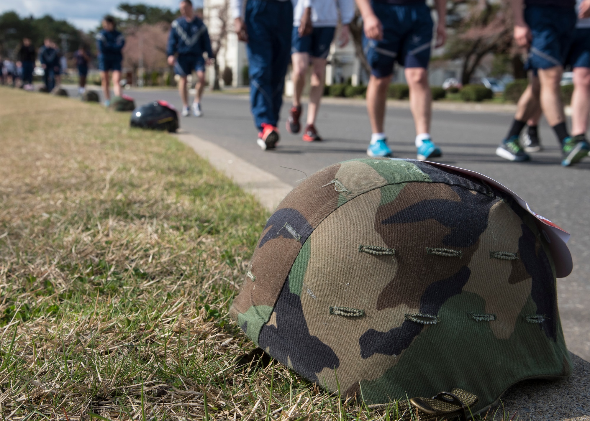 Military helmets line Risner Circle during Resilient Airman Day at Misawa Air Base, Japan, April 15, 2016. During the “Silent Walk” portion of the day, Misawa military members passed by helmets topped with red cards describing sexual assaults occurring during fiscal year 2015 and 2016. The purpose of this event was to highlight the necessity of caring for one’s wingman and bring the severity of the issue home. (U.S. Air Force photo by Airman 1st Class Jordyn Fetter)