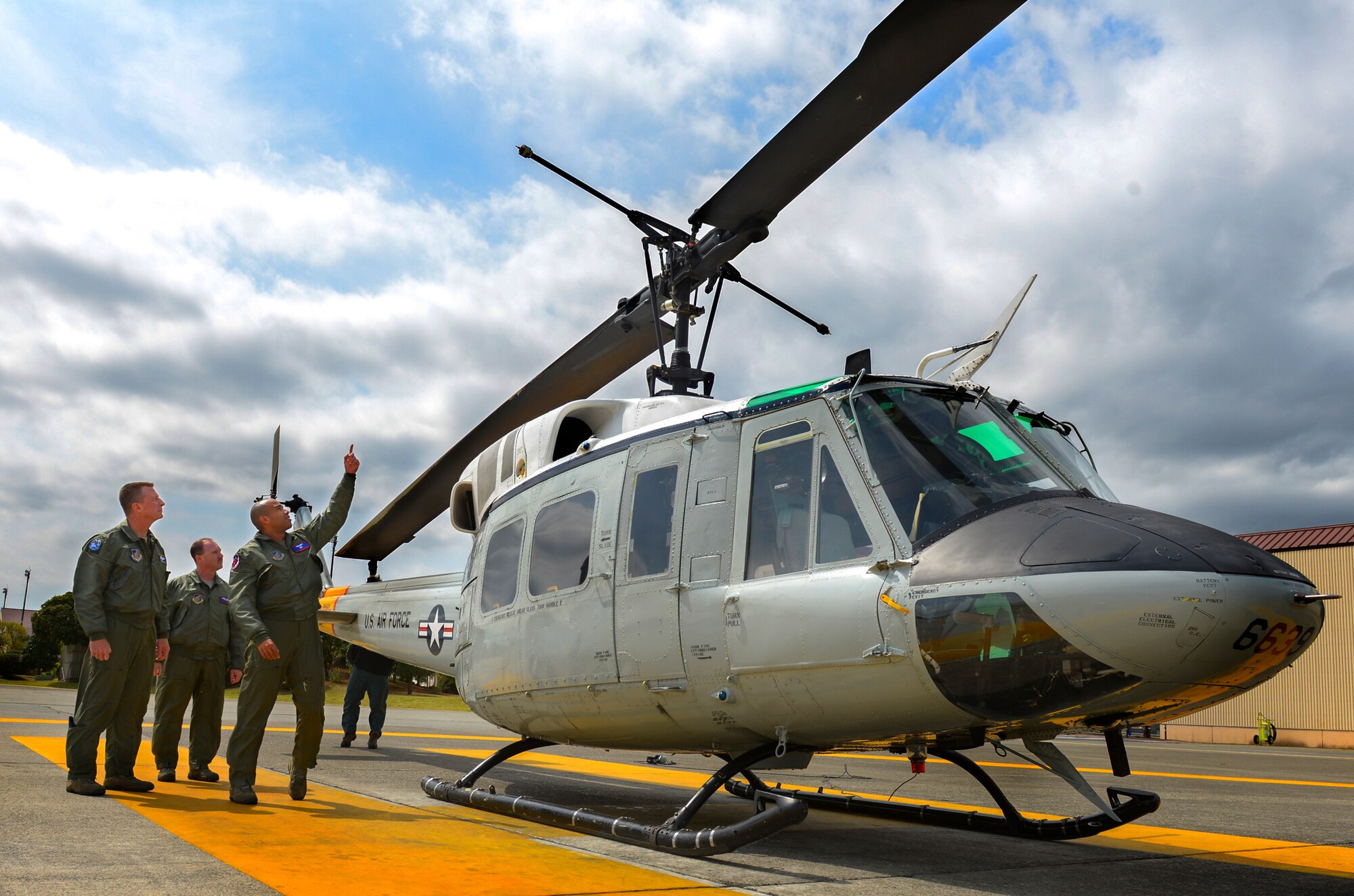 Capt. Brandon Jones, 459th Airlift Squadron chief of standards and evaluation, right, and Tech. Sgt. David Jacobs, 459 AS special missions aviator, explain the basic mechanics of a UH-1N Iroquois to Lt. Gen. John Dolan, U.S. Forces, Japan and 5th Air Force commander, at Yokota Air Base, Japan, April 11, 2016. Jones and Jacobs assisted Dolan with piloting a UH-1N as part of a key staff pilot course, a tradition conducted to help leadership better understand the capabilities within their command. (U.S. Air Force photo by Airman 1st Class Elizabeth Baker/Released)
