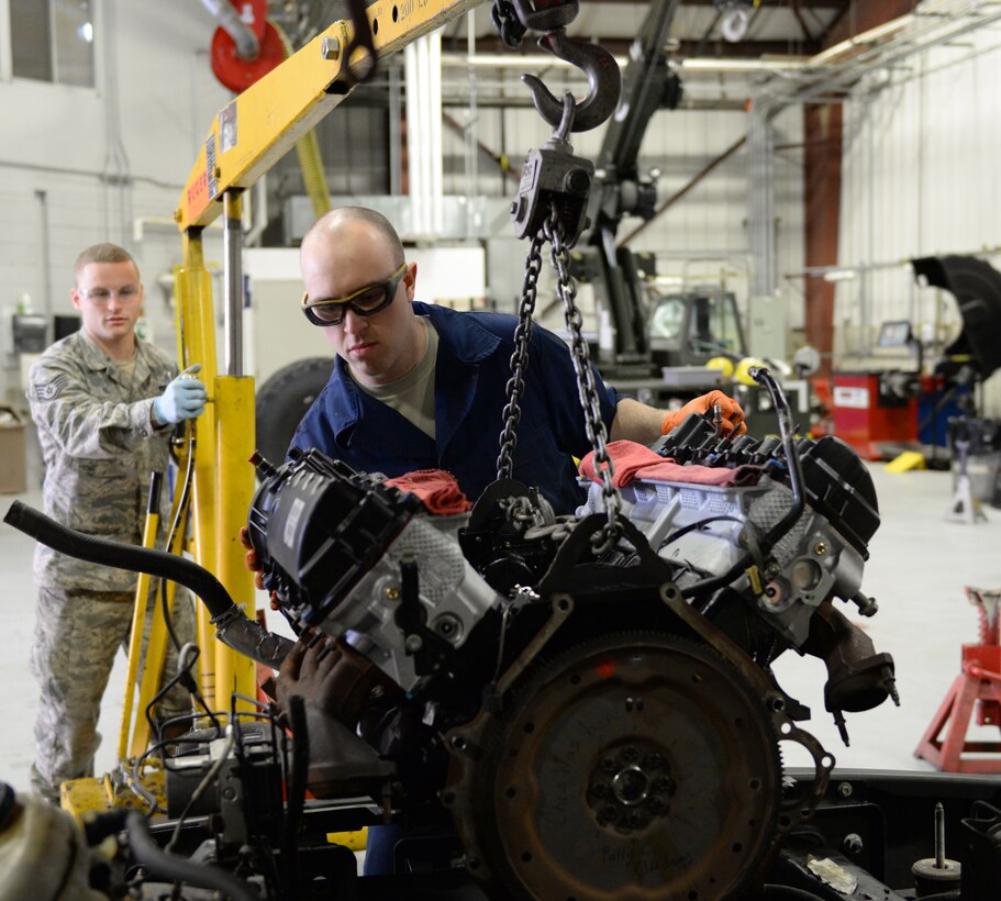 U.S. Air Force Staff Sgt. Chris Wood, (left) and Airman 1st Class Patrick Clifford move a new  Ford 5.4 liter V8 engine in a 2008 Ford F-150 pickup truck, April 14, 2016, Pease Air National Guard Base, N.H. The Airmen are special purposes vehicle technicians assigned to the Vehicle Maintenance Branch, 157th Logistics Readiness Squadron, New Hampshire Air National Guard. (U.S. Air National Guard photo by Staff Sgt. Curtis J. Lenz)