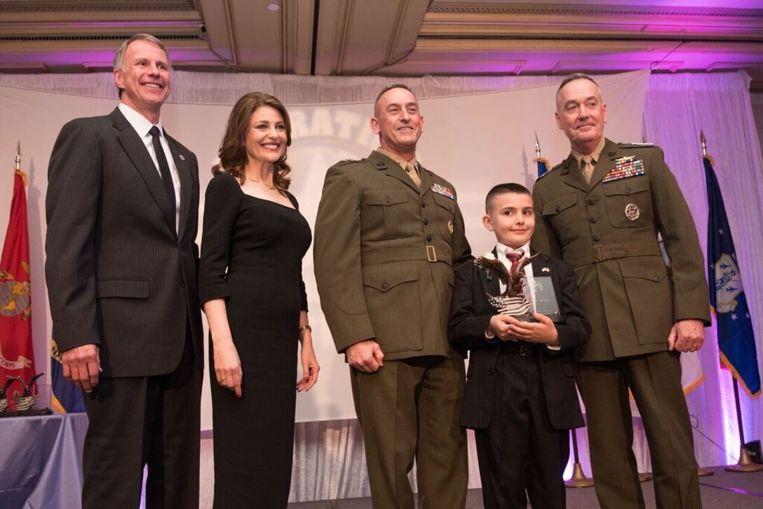 Christian Fagala, 9, of Quantico, Va., receives the Operation Homefront 2016 Marine Corps Military Child of the Year Award, during Operation Homefront’s Eighth Annual Military Child of the Year® Award Ceremony here on Thursday, April 14.  Presenting the award are Marine Corps Gen. Joseph F. Dunford Jr., Chairman of the Joint Chiefs of Staff (right); Maj. Gen. James W. Lukeman, Commanding General, Marine Corps Training and Education Command; Catherine Blades, Chairwoman of the Board at Operation Homefront and Senior Vice President, Corporate Communications, at Aflac; and Brig. Gen. (ret.) John I. Pray Jr., President and CEO of Operation Homefront.  