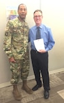 DLA Troop Support Commander Army Brig. Gen. Charles Hamilton presents Evan Eisenberg with a Commander’s Coin and congratulations letter March 31, 2016 for earning the DLA Acquisition Professional Supporting Small Business award. Eisenberg was selected for the award for planning and awarding two contracts for the Navy Working Uniform to small businesses in fiscal 2015. 