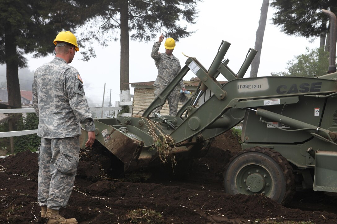 U.S. Army Staff Sgt. John Langstrom and Pfc. Curtis Reeves with the 1038th Engineers guide construction equipment at the construction site for the Aldea Polopon clinic at Palo Gordo, Guatemala, March 29, 2016. Task Force Red Wolf and Army South conducts Humanitarian Civil Assistance Training to include tactical level construction projects and Medical Readiness Training Exercises providing medical access and building schools in Guatemala with the Guatemalan Government and non-government agencies from 05MAR16 to 18JUN16 in order to improve the mission readiness of US Forces and to provide a lasting benefit to the people of Guatemala. (U.S. Army photo by Sgt. Prosper Ndow/Released)