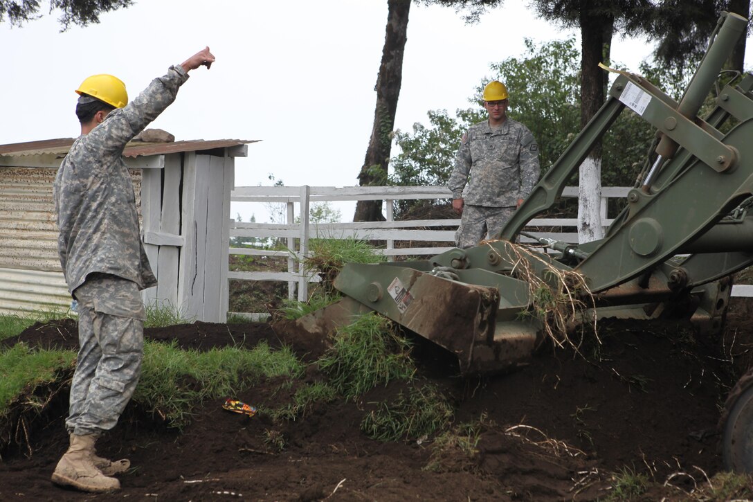 U.S. Army Staff Sgt. John Langstrom and Pfc. Curtis Reeves with the 1038th Engineers guide construction equipment at the construction site for the Aldea Polopon clinic at Palo Gordo, Guatemala, March 29, 2016. Task Force Red Wolf and Army South conducts Humanitarian Civil Assistance Training to include tactical level construction projects and Medical Readiness Training Exercises providing medical access and building schools in Guatemala with the Guatemalan Government and non-government agencies from 05MAR16 to 18JUN16 in order to improve the mission readiness of US Forces and to provide a lasting benefit to the people of Guatemala. (U.S. Army photo by Sgt. Prosper Ndow/Released)