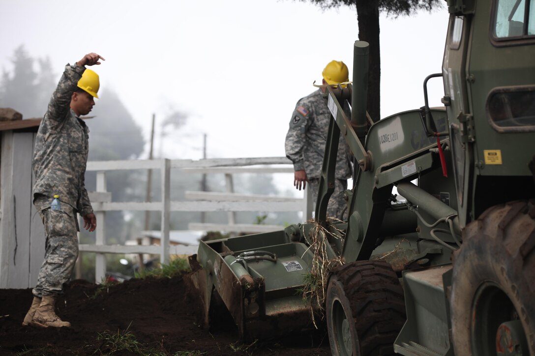 U.S. Army Staff Sgt. John Langstrom and Pfc. Curtis Reeves with the 1038th Engineers guide construction equipment at the construction site for the Aldea Polopon clinic at Palo Gordo, Guatemala, March 29, 2016. Task Force Red Wolf and Army South conducts Humanitarian Civil Assistance Training to include tactical level construction projects and Medical Readiness Training Exercises providing medical access and building schools in Guatemala with the Guatemalan Government and non-government agencies from 05MAR16 to 18JUN16 in order to improve the mission readiness of US Forces and to provide a lasting benefit to the people of Guatemala. (U.S. Army photo by Sgt. Prosper Ndow/Released)