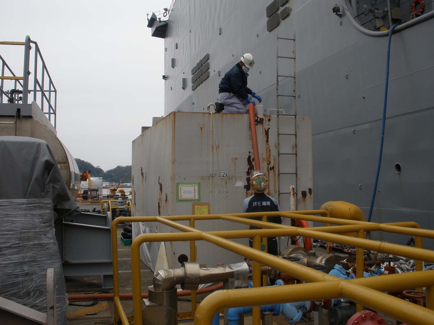 Employees from Japan Iron Engineering work on above ground holding tanks used for storing hazardous waste materials removed from Navy at Fleet Activities, Yokuska, Japan. Photo by Yasuo Tsunoda