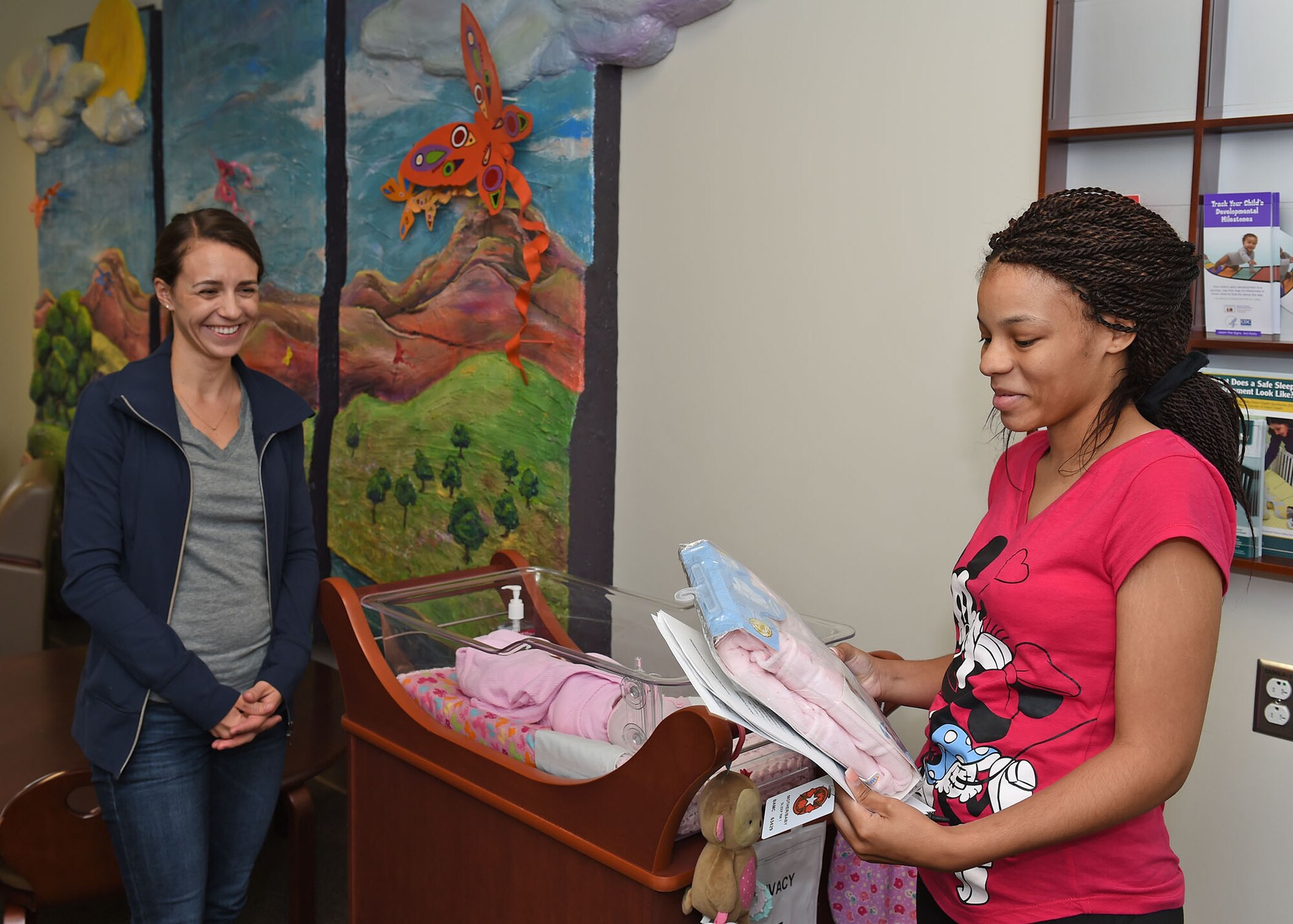 Kelly Banachowski, Wilford Hall Auxiliary service chair (left), presents Jasmine Reese (right) with the first neonatal intensive care unit Halo SleepSack March 23 at the San Antonio Military Medical Center. Reese received the gift before leaving SAMMC with her newborn daughter. Donated by the WHA, the SleepSacks are used at SAMMC to promote the safety of sleeping newborns. (U.S. Air Force photo/Tech. Sgt. Christopher Carwile)