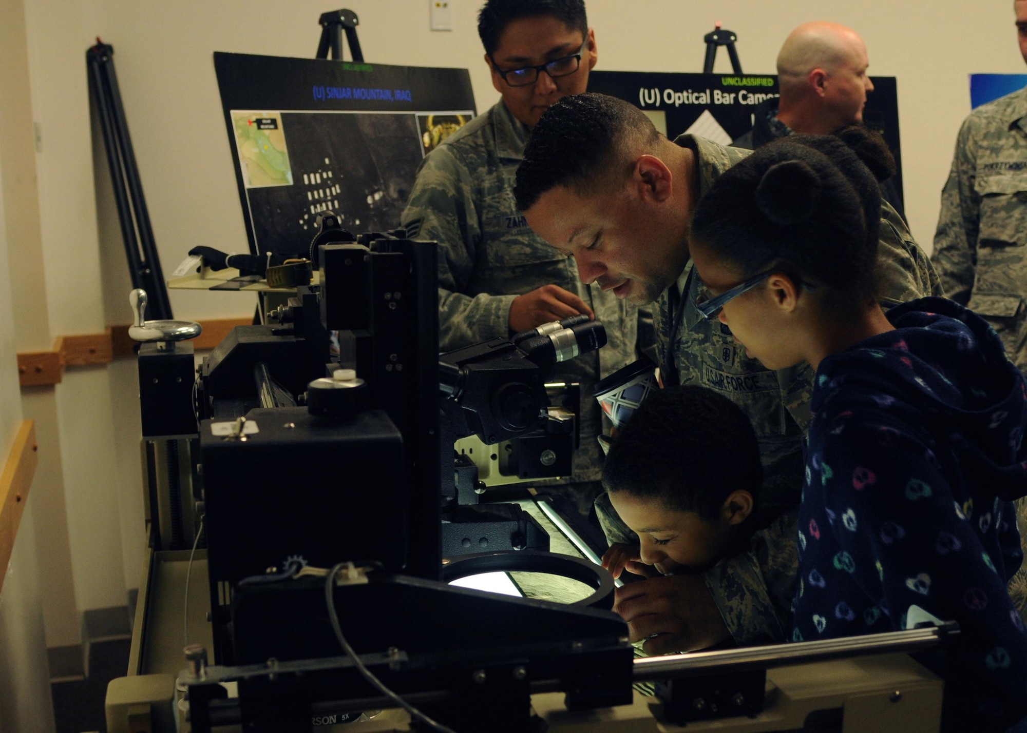 Master Sgt. Charles examines optical bar camera film with his children at an open house for the 548th Intelligence, Surveillance and Reconnaissance Group at Beale Air Force Base, April 13, 2016. The 548th ISR Group opened their doors, allowing family members to get an inside look at the work their Airmen do on a daily basis. (U.S. Air Force photo by Airman 1st Class Jessica B.  Nelson/Released)