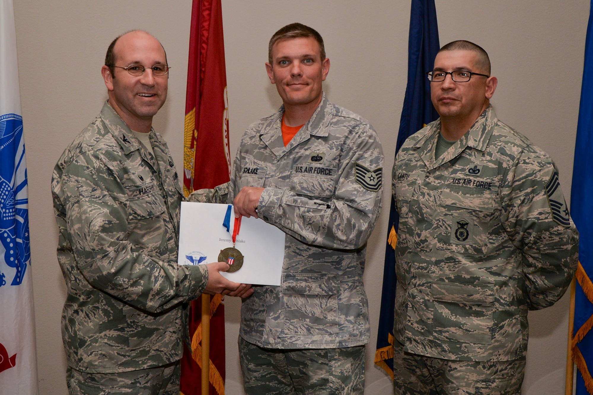 U.S. Air Force Col. Christopher Harris, 17th Mission Support Group Commander, and Chief Master Sgt. Jessie Cantu, 17th MSG acting superintendent, present the President’s Volunteer Service Award Bronze medal to Tech. Sgt. Jeremy Schlake, 17th Training Support Squadron, during the volunteer recognition ceremony at the Event Center on Goodfellow Air Force Base, Texas, April 15, 2016. The bronze medal is awarded to individuals who logged between 100 and 249 volunteer hours. (U.S. Air Force photo by Airman 1st Class Randall A.S. Moose/Released)