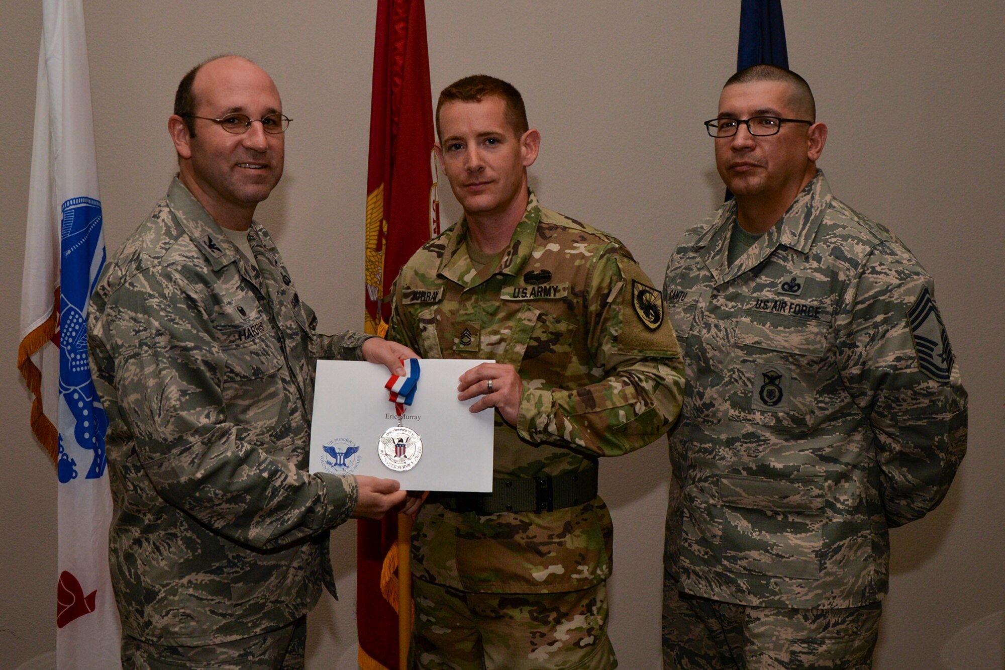 U.S. Air Force Col. Christopher Harris, 17th Mission Support Group Commander, and Chief Master Sgt. Jessie Cantu, 17th MSG acting superintendent, present the President’s Volunteer Service Award Silver medal to Sgt. 1st Class Eric Murray, 344th Military Intelligence Battalion, during the volunteer recognition ceremony at the Event Center on Goodfellow Air Force Base, Texas, April 15, 2016. The silver medal is awarded to individuals who logged between 250 and 499 volunteer hours. (U.S. Air Force photo by Airman 1st Class Randall A.S. Moose/Released)