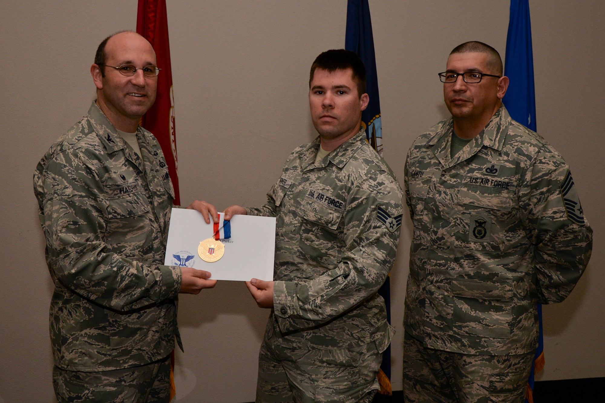 U.S. Air Force Col. Christopher Harris, 17th Mission Support Group Commander, and Chief Master Sgt. Jessie Cantu, 17th MSG acting superintendent, present the President’s Volunteer Service Award Gold medal to Senior Airman Robert Parker, 17th Communications Squadron, during the volunteer recognition ceremony at the Event Center on Goodfellow Air Force Base, Texas, April 15, 2016. The gold medal is awarded to individuals who logged 500 or more volunteer hours. (U.S. Air Force photo by Airman 1st Class Randall A.S. Moose/Released)