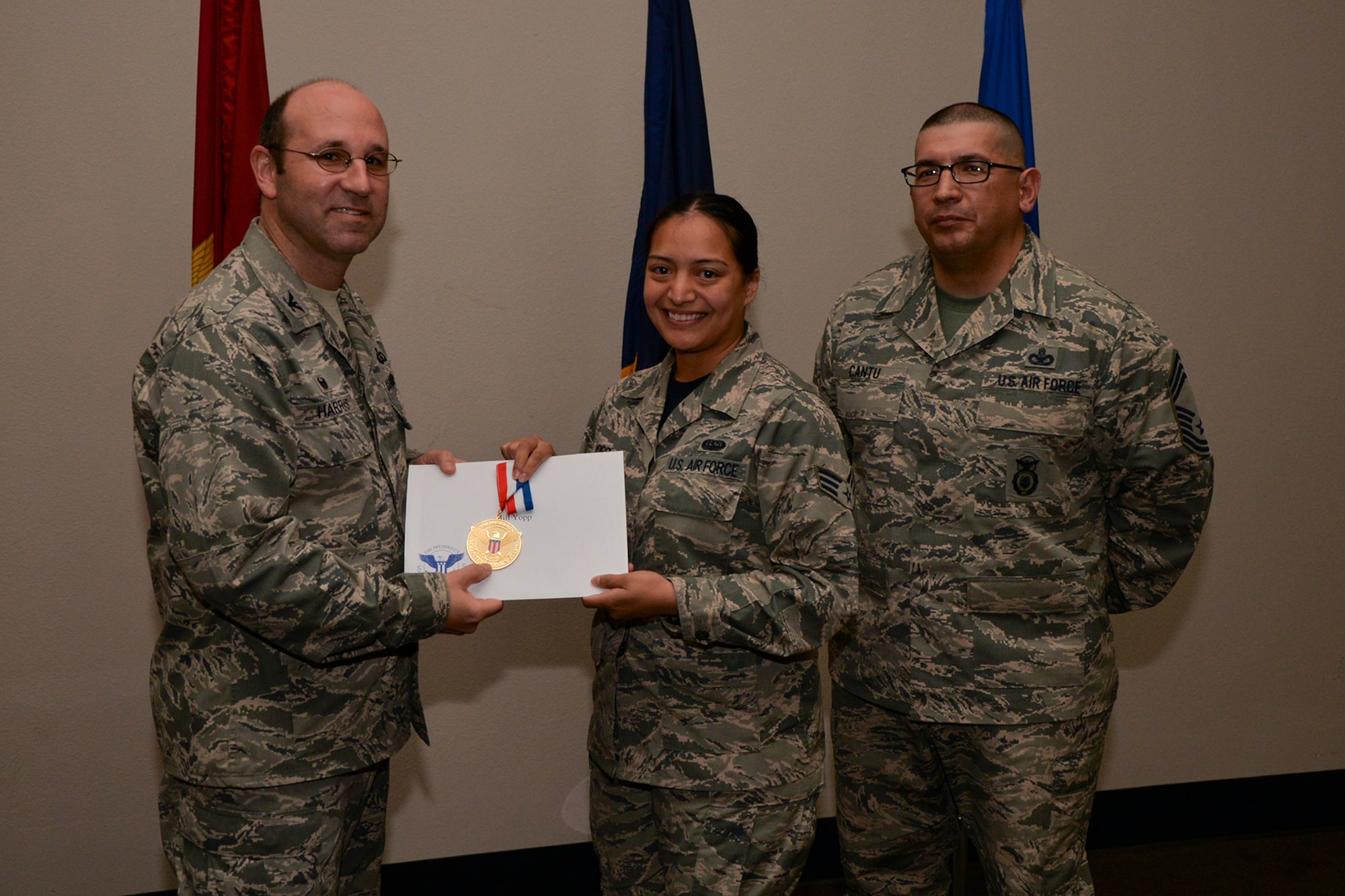 U.S. Air Force Col. Christopher Harris, 17th Mission Support Group Commander, and Chief Master Sgt. Jessie Cantu, 17th MSG acting superintendent, present the President’s Volunteer Service Award Gold medal to Senior Airman Jill Yopp, 17th Communications Squadron, during the volunteer recognition ceremony at the Event Center on Goodfellow Air Force Base, Texas, April 15, 2016. The gold medal is awarded to individuals who logged 500 or more volunteer hours. (U.S. Air Force photo by Airman 1st Class Randall A.S. Moose/Released)