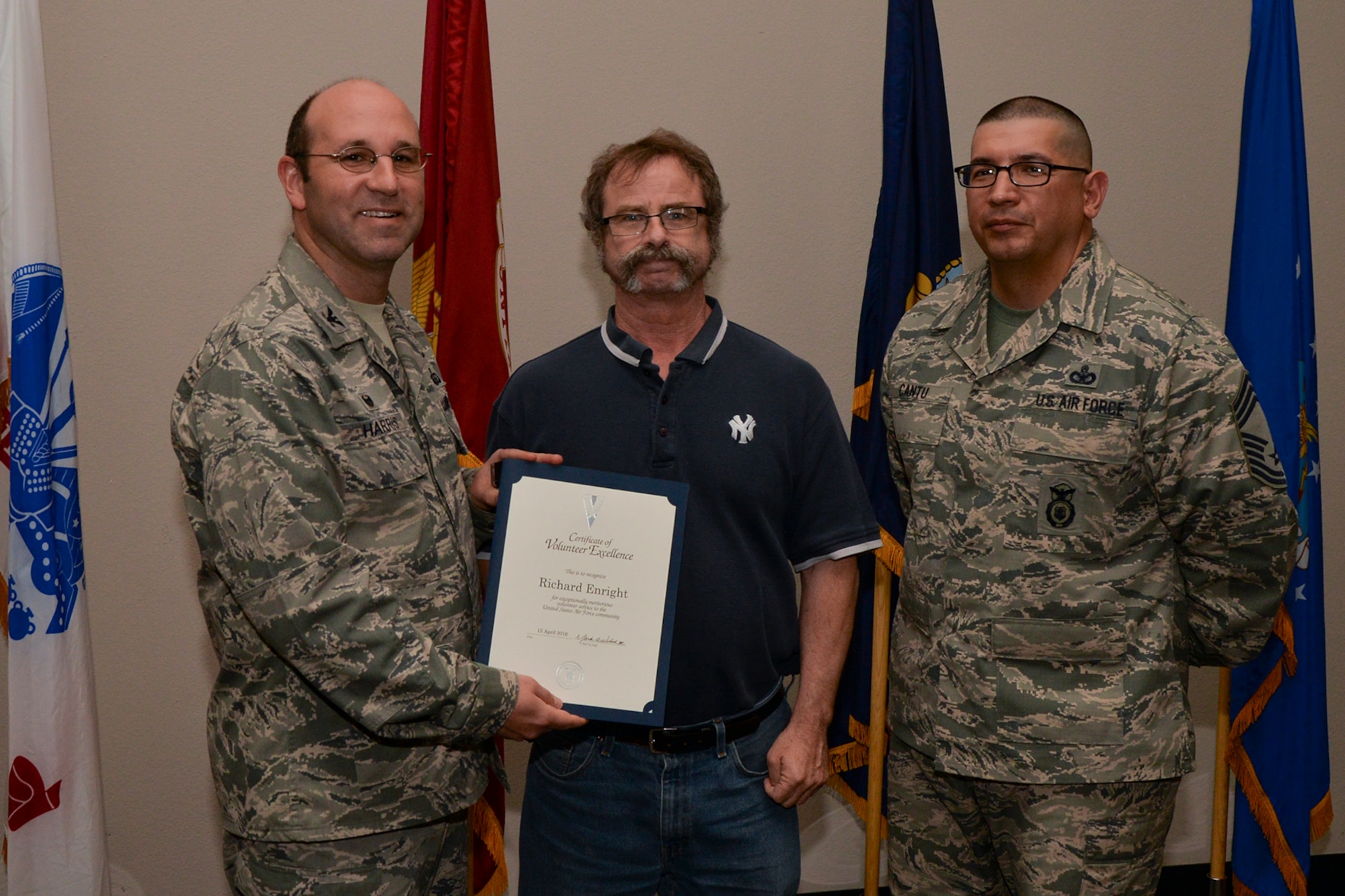 U.S. Air Force Col. Christopher Harris, 17th Mission Support Group Commander, and Chief Master Sgt. Jessie Cantu, 17th MSG acting superintendent, present the Volunteer Excellence Award to Richard Enright, 17th Civil Engineer Squadron, during the volunteer recognition ceremony at the Event Center on Goodfellow Air Force Base, Texas, April 15, 2016. The Volunteer Excellence Award recognizes federal civilian employees, family members, and federal civilian and military retirees who perform outstanding volunteer community service of a sustained, direct and consequential nature. (U.S. Air Force photo by Airman 1st Class Randall A.S. Moose/Released)