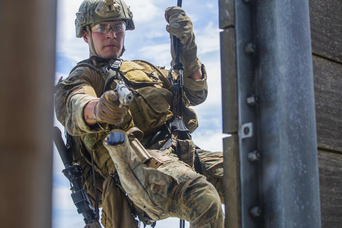 Marine Corps Cpl. Jacob Carpenter simulates attacking a target through a window while rappelling down a tower at Camp Hansen in Okinawa, Japan, April 14, 2016. Carpenter is assigned to Maritime Raid Force, 31st Marine Expeditionary Unit. Marine Corps photo by Lance Cpl. Carl King Jr.