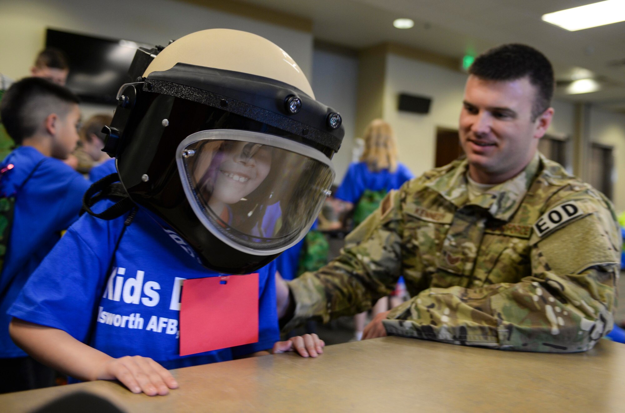 Aidan Serrano, son of Airman 1st Class Shannon Serrano, 28th Contracting Squadron contract administrator, tries on an A9 explosive ordnance disposal bomb helmet with Staff Sgt. Jace Kennedy, 28th Civil Engineer Squadron EOD technician, during the kids’ deployment line at Ellsworth Air Force Base, S.D., April 9, 2016. The event offered children an opportunity to participate in a simulated deployment out-processing line, watch a military working dog demonstration, view inert grenades, and test flight suit equipment. (U.S. Air Force photo by Airman 1st Class Sadie Colbert/Released)