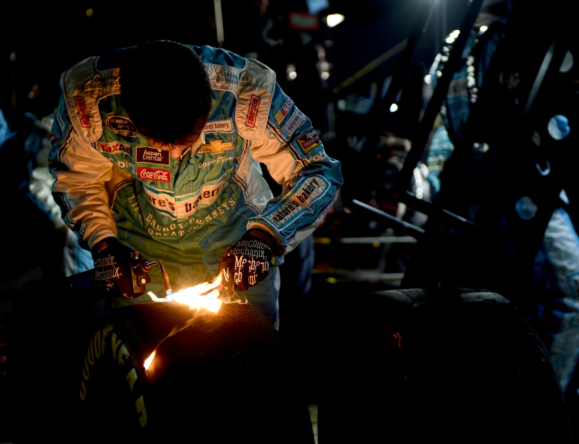 A pit crew member prepares a used tire for a tread-wear inspection April 9, 2016, at the Texas Motor Speedway, Fort Worth, Texas. A small layer of rubber is removed from the tire with a blowtorch and scraper so that a tread-wear indicator device can more accurately read the amount of rubber lost during the previous laps. Before the race began, U.S. Air Force Gen. David L. Goldfein, United States Air Force vice chief of staff, administered the Oath of Enlistment to a group of men and women in the Air Force Delayed Entry Program. (U.S. Air Force photo by Senior Airman Alexander Guerrero/Released)