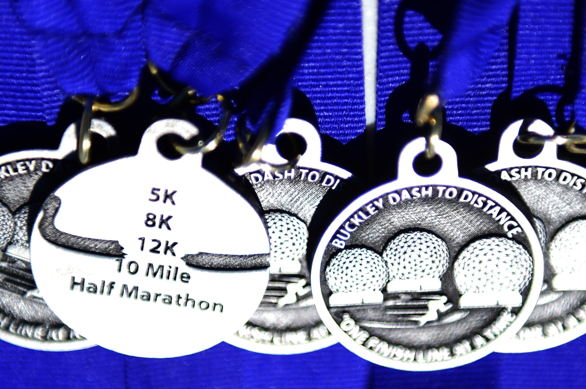 Participation medals lay on a table April 14th, 2016, during the Dash to Distance 5K on Buckley Air Force Base, Colo. The Dash to Distance race series consists 5 events, starting with a 5K and ending with a half marathon; races will run from April-September. (U.S. Air Force photo by Senior Airman Racheal E. Watson/Released)