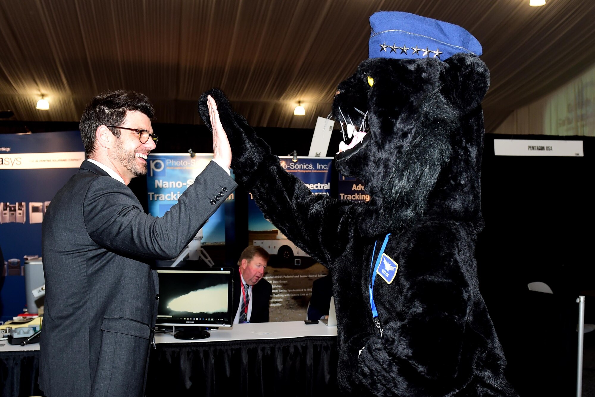 Buck Lee, Buckley Air Force Base mascot, gives a Space Symposium visitor a high five April 12, 2016, at the Broadmoor Hotel in Colorado Springs, Colo. Air Force Space Command held a booth during the Space Symposium and Buck Lee made an appearance to show what Buckley AFB has been doing. (U.S. Air Force photo by Staff Sgt. Katrina Brisbin/Released)