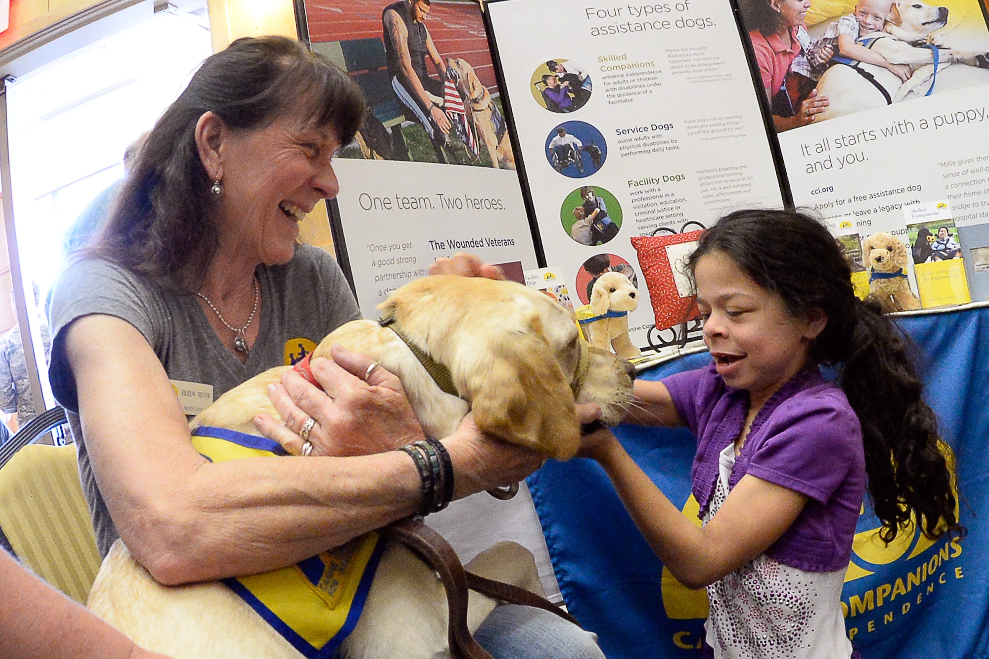 Illene Seavier, K-9 Champions for Disabilities, allows her dog Buttercup to get a friendly rub from Isabelle Wellman, during the Special Needs Summit April 6 at Hill Air Force Base. The event is held annually to expose base personnel and their families with the wide range of special needs services and activities in the area. (U.S. Air Force photo by Todd Cromar)