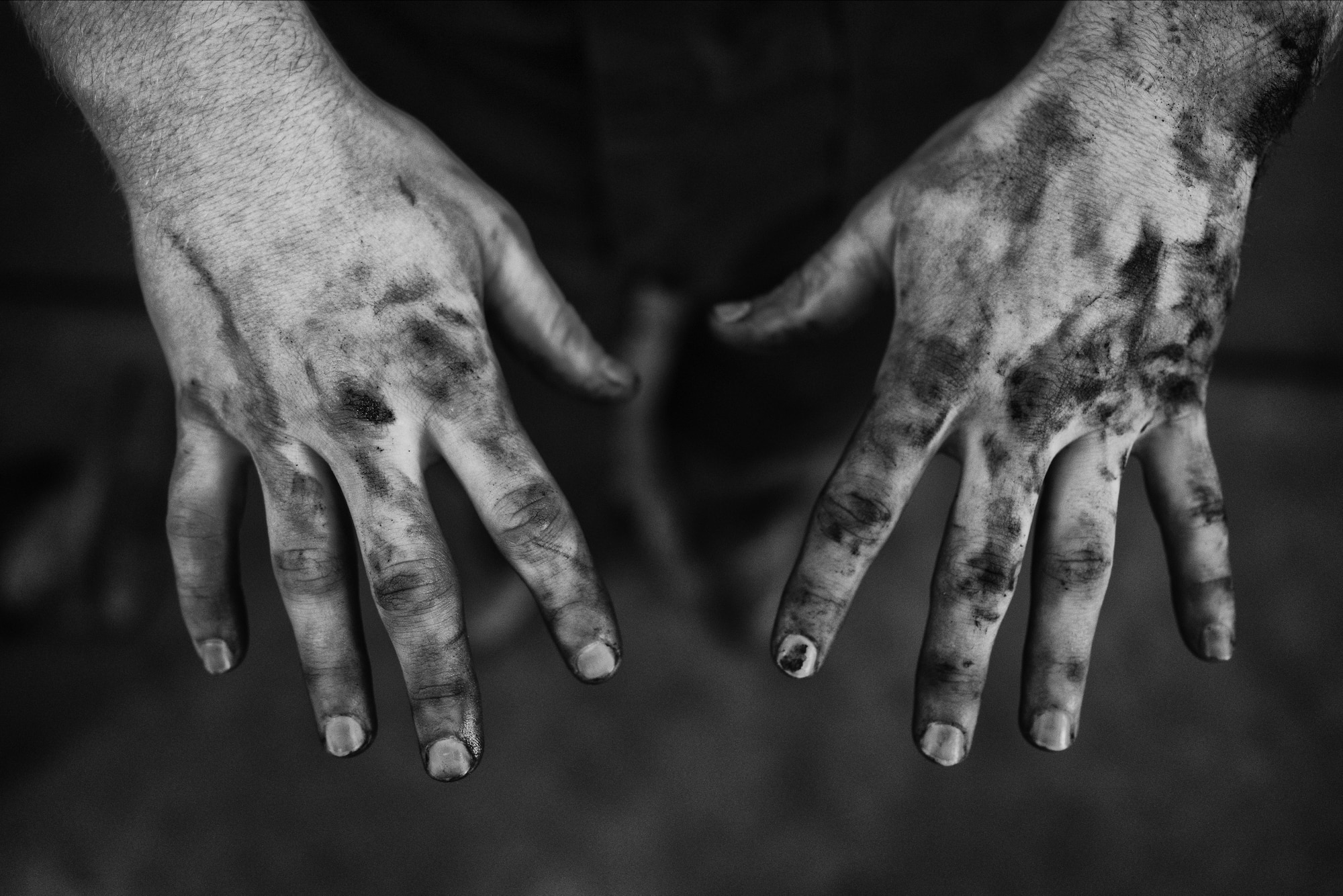 Airman 1st Class Justin Stephens, 374th Logistics Readiness Squadron vehicle maintenance apprentice, reveals his oil-covered hands after repairing a government vehicle at Yokota Air Base, Japan, April 13, 2016. The vehicle maintenance shop services more than 1,100 vehicles valued at $118 million. (U.S. Air Force photo by Senior Airman Delano Scott/Released)