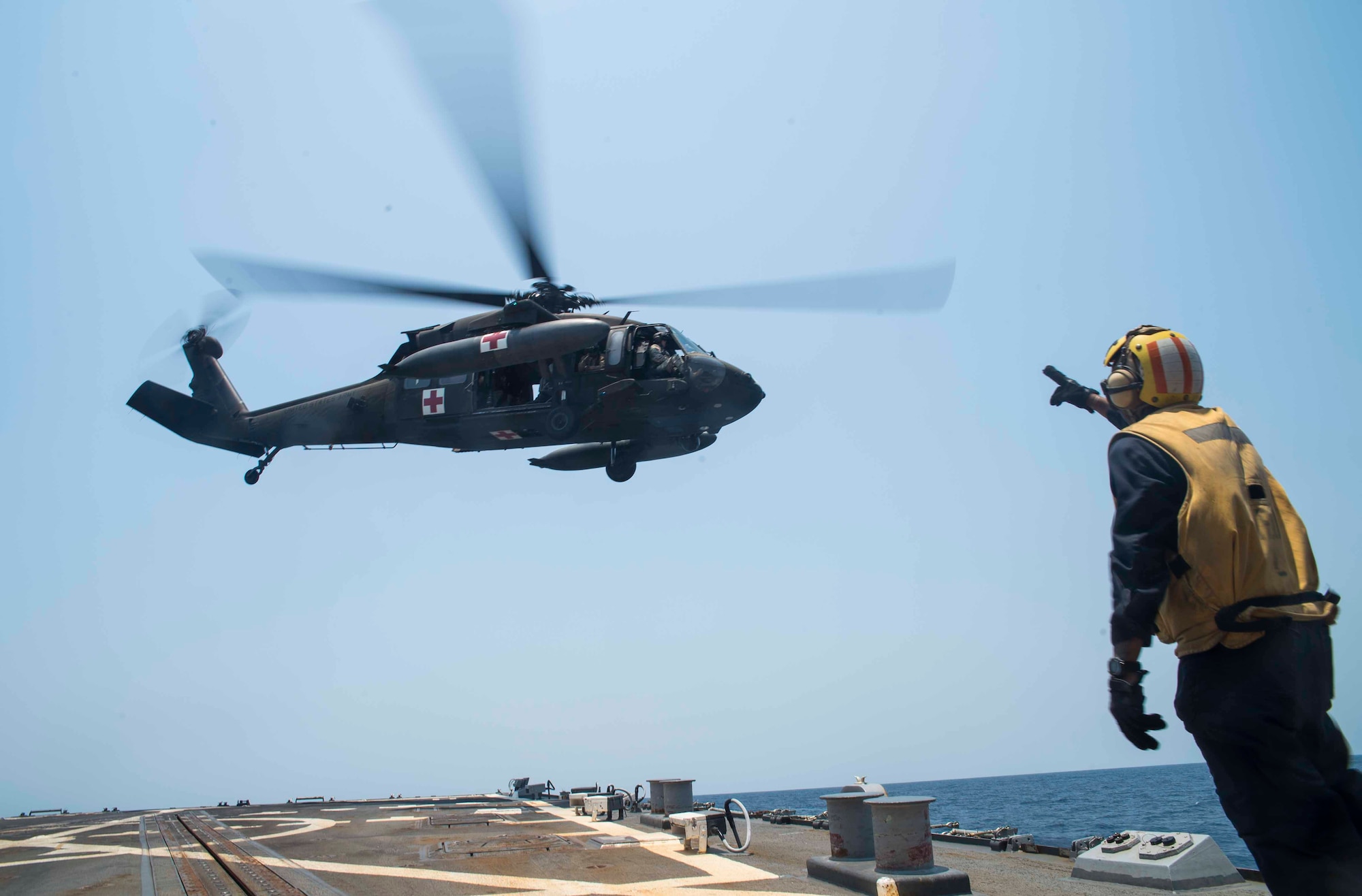 A U.S. Navy sailor signals to the crew of a UH-60 Blackhawk assigned to the 1st Battalion, 228th Aviation Regiment, Joint Task Force Bravo at Soto Cano Air Base, Honduras, during the Blackhawk crew’s deck landing qualification off the coast of Honduras, April 14, 2016. Seventeen pilots and 16 crew chiefs qualified, performing approximately 80 deck landings on the USS Lassen. (U.S. Air Force photo by Staff Sgt. Siuta B. Ika)