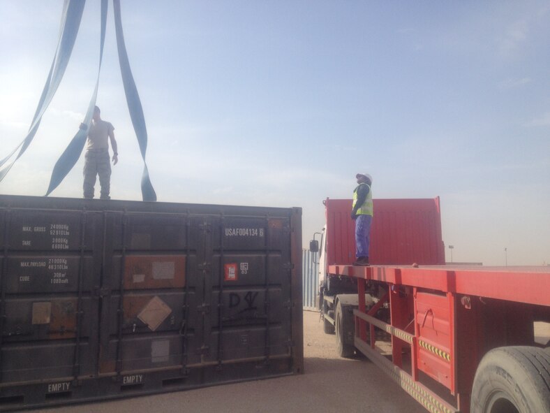 Senior Airman Thomas Latham (left), 379th Expeditionary Logistic Readiness Squadron unit pass coordinator, secure straps on a container to prepare for transport from Al Udeid Air Base, Qatar to the Defense Logistics Agency in Southwest Asia. (U.S. Air Force photo courtesy of Master Sgt. Shobha Parker/Released) 