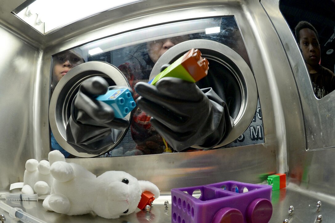 Students use a glove box to play an educational game as part of a Defense Department display at the USA Science and Engineering Festival in Washington, D.C., April 15, 2016. DoD photo by EJ Hersom