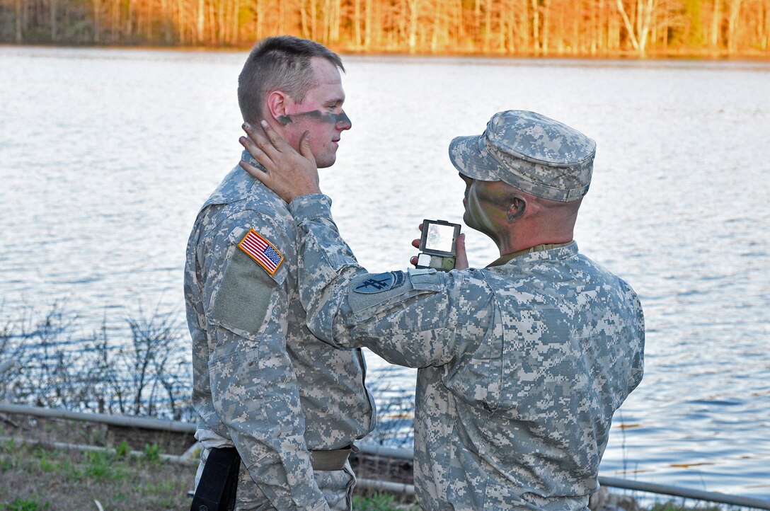 Staff Sgt. Larry James applies field camouflage to 1st Lt. Benton Harvey at the Indiana National Guard’s Muscatatuck Urban Training Center as their unit, the Army Reserve’s 346th Psychological Operations Company (Airborne) out of Columbus, Ohio, conducts training on Wednesday, April 13. (Indiana National Guard photo by Master Sgt. Brad Staggs, Atterbury-Muscatatuck Public Affairs)